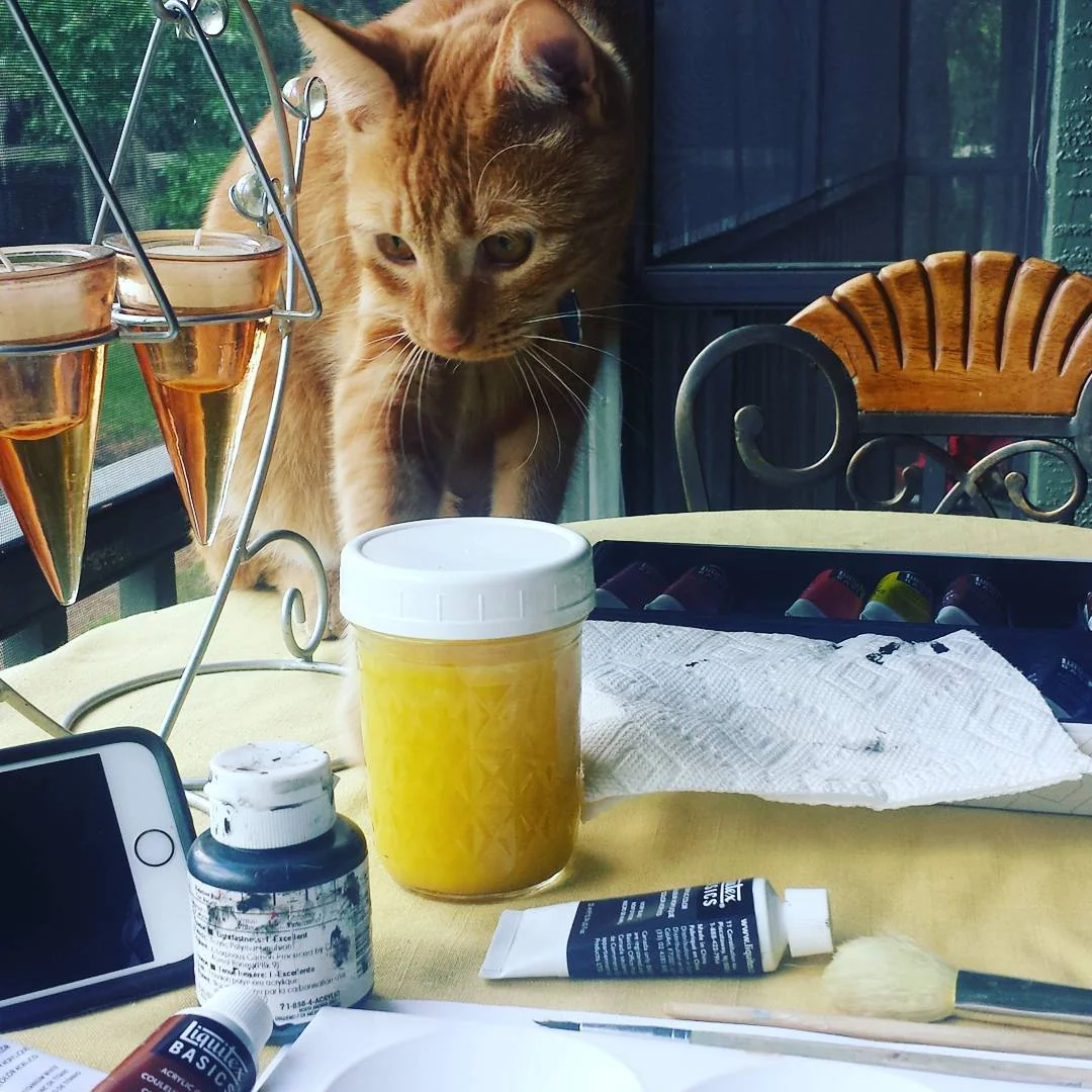 Coby the cat beside paints and art supplies