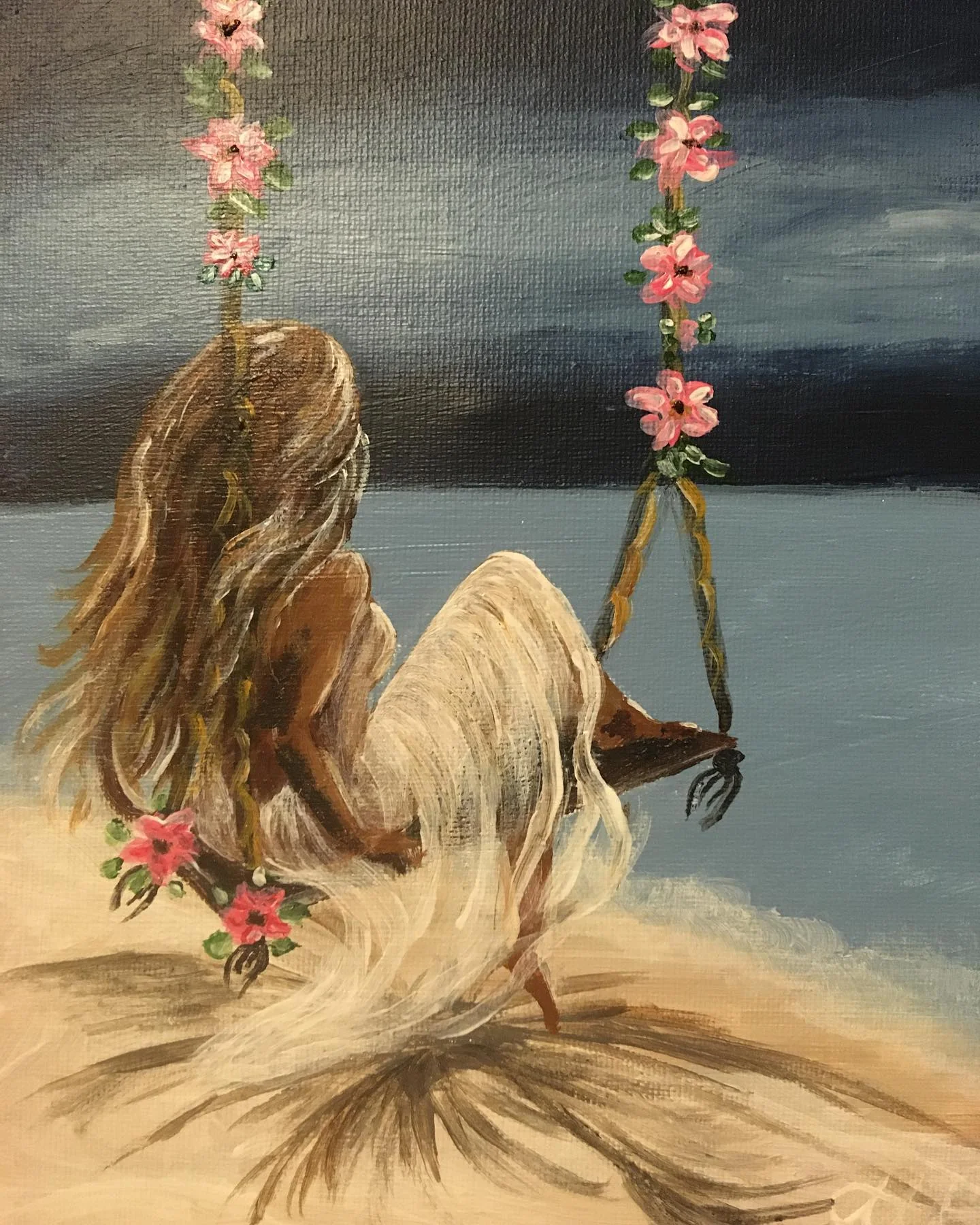 A woman on a flower-covered swing overlooking the sea